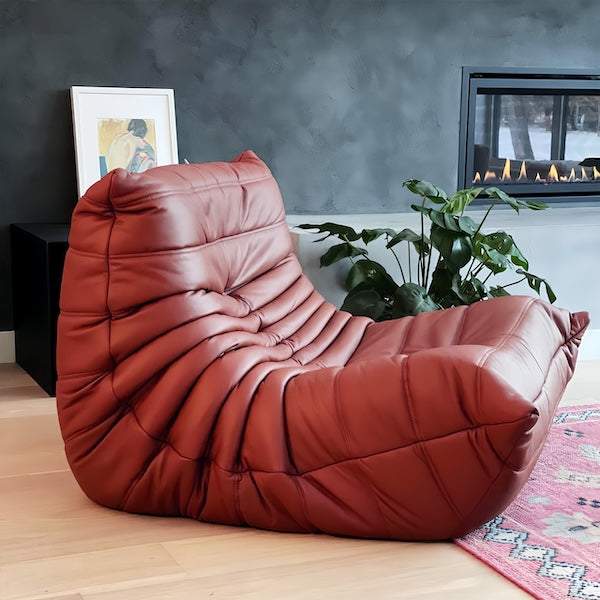 Togo Chair Fiber Leather Replica in deep red with ergonomic design and hand-sewn tuft detailing in modern living room setting