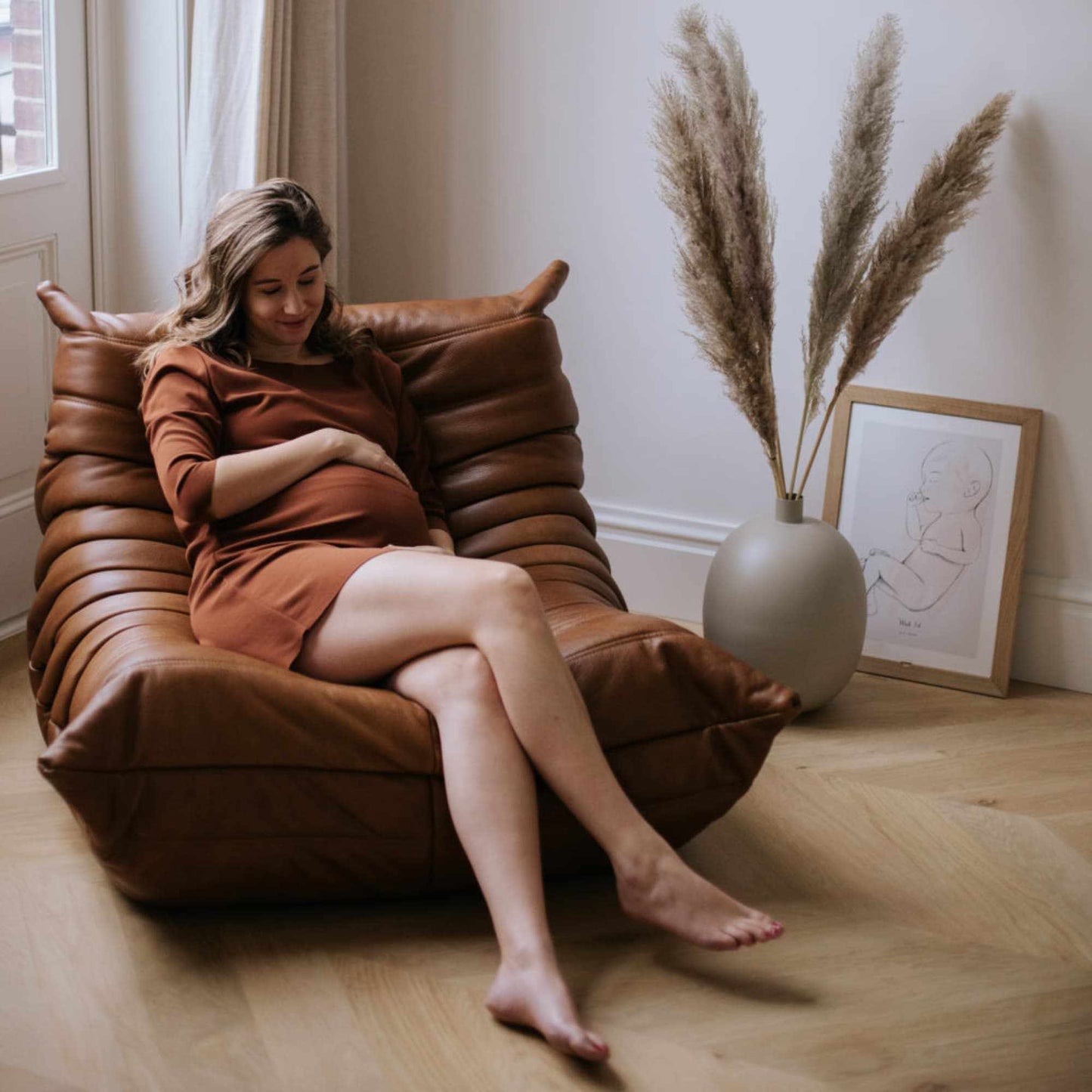 Woman sitting on brown Togo Chair fiber leather replica in cozy living room